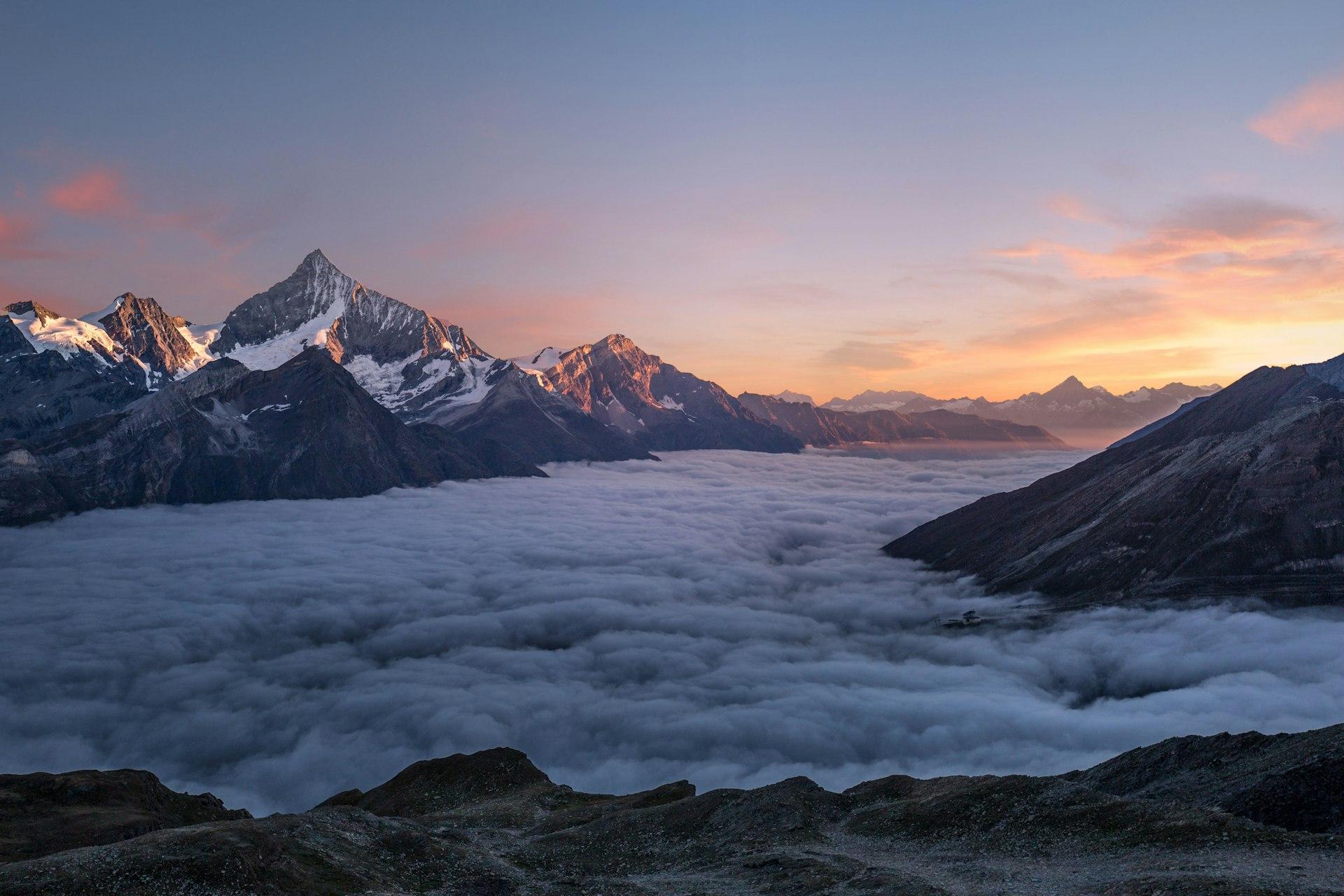 Snow-capped mountain peaks above a glacial valley at sunrise